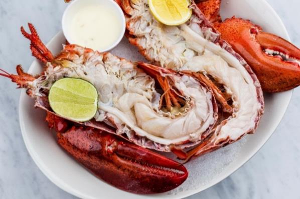 A plate of lobster with lemons and sauces Description automatically generated
